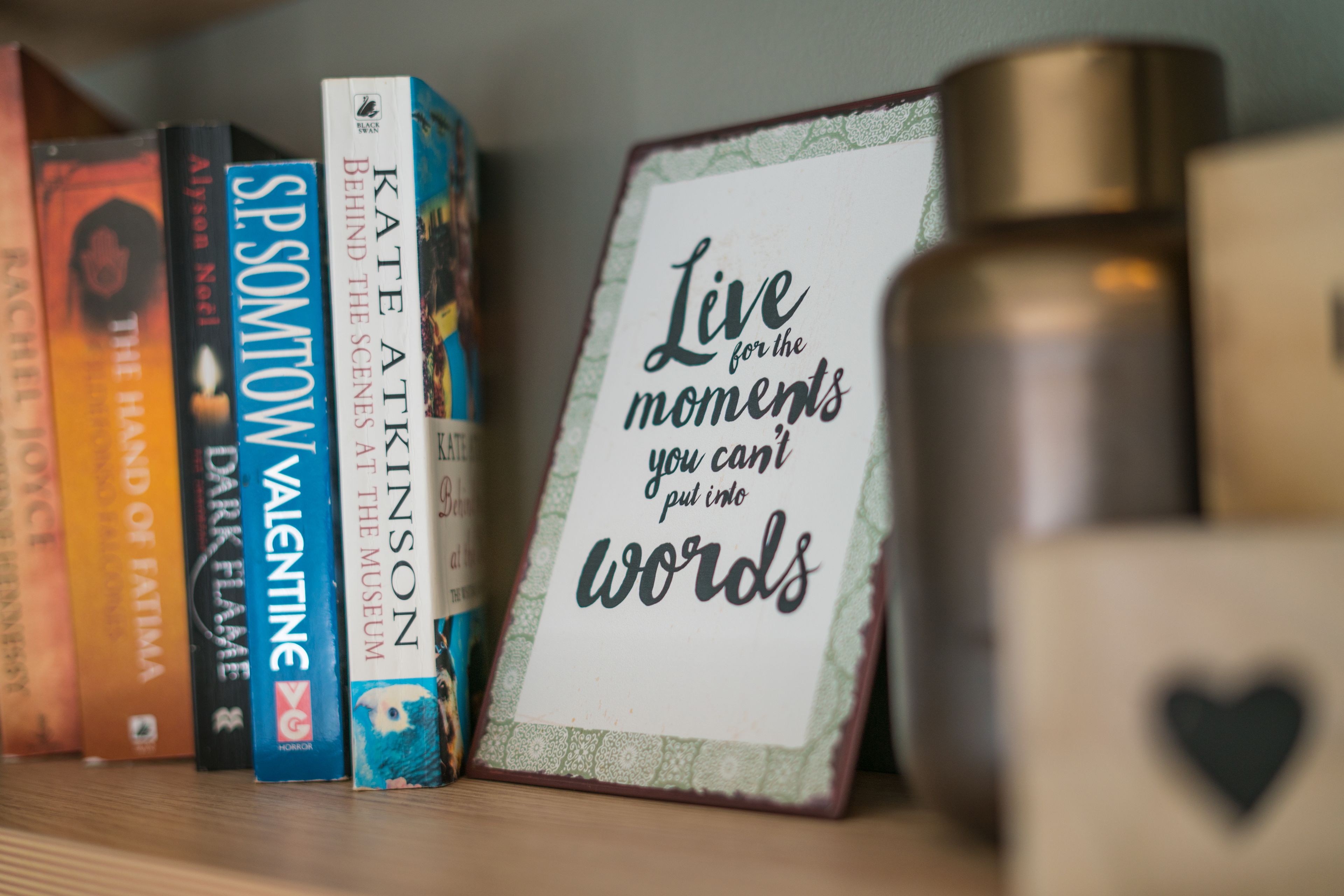 A bookshelf with books and a framed inspirational quote.