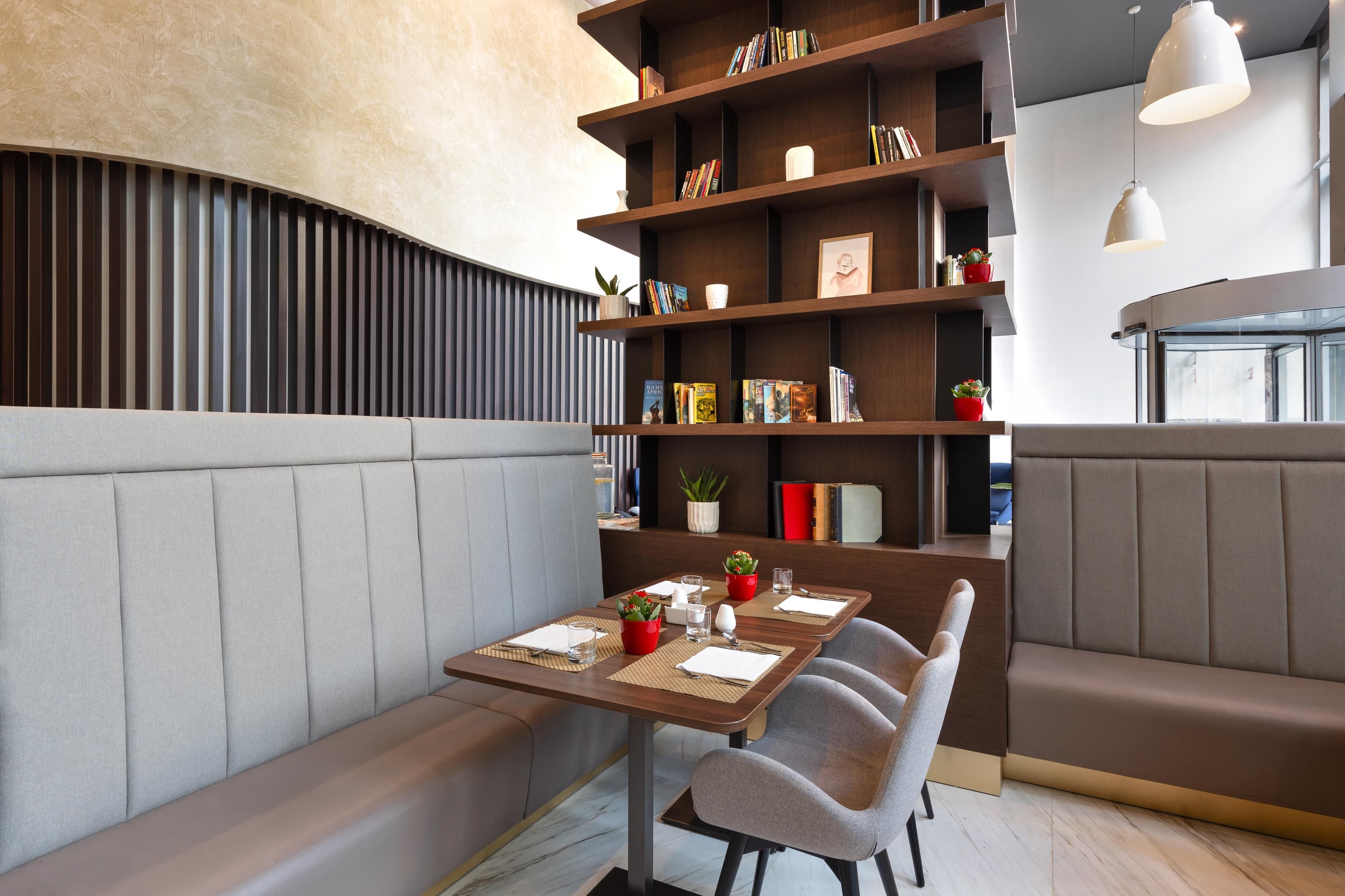 Un comedor moderno con asientos tipo cabina, una estantería de madera y una mesa preparada para dos.