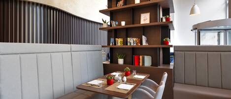 Un comedor moderno con asientos tipo cabina, una estantería de madera y una mesa preparada para dos.