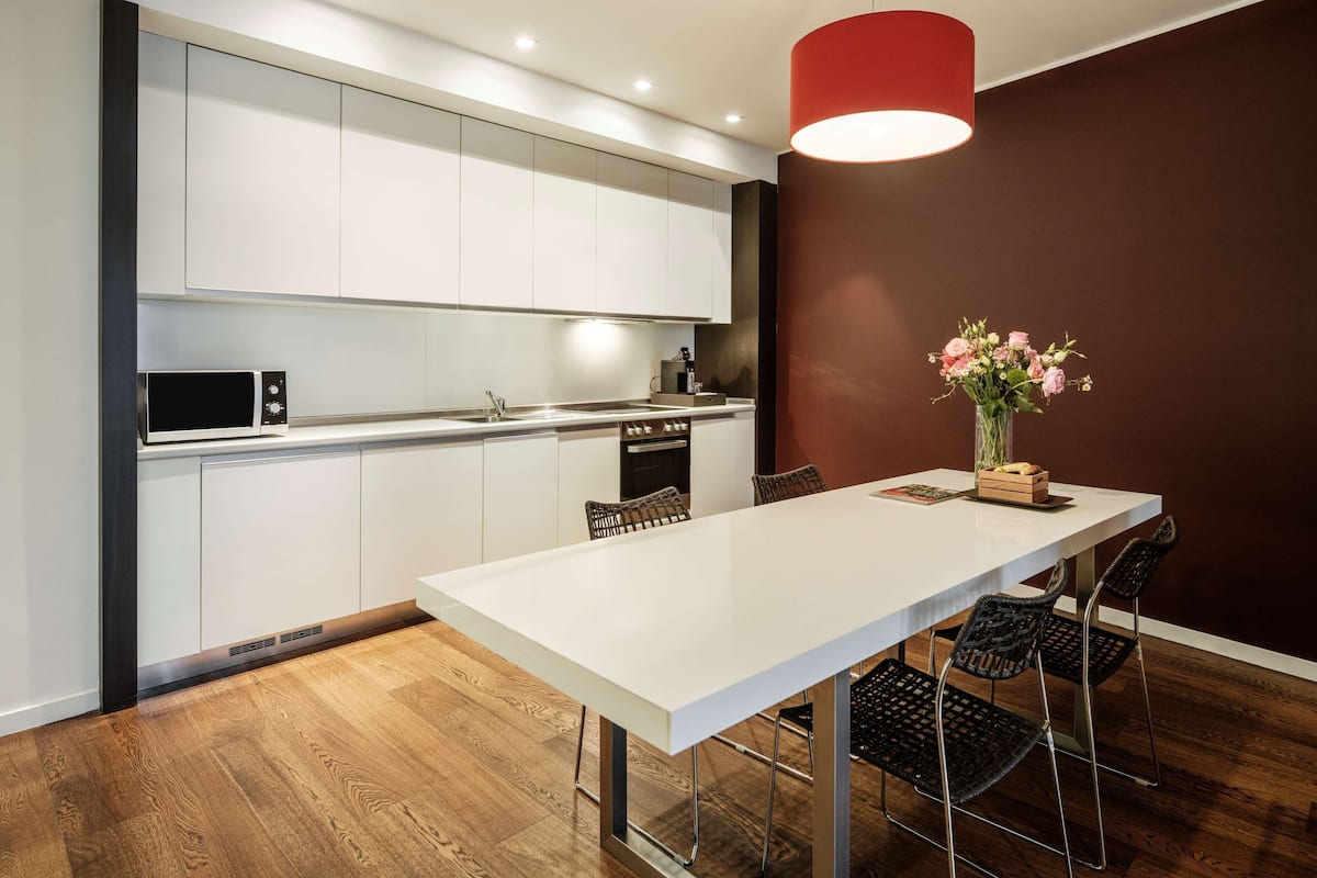 A modern kitchen with white cabinets, a microwave, and a red pendant light.