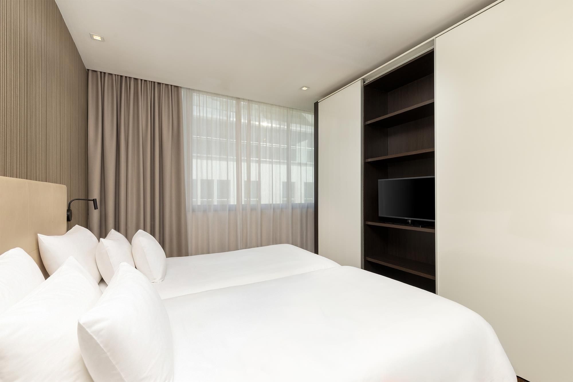 Une chambre d’hôtel avec un grand lit, une armoire et une fenêtre avec des rideaux.