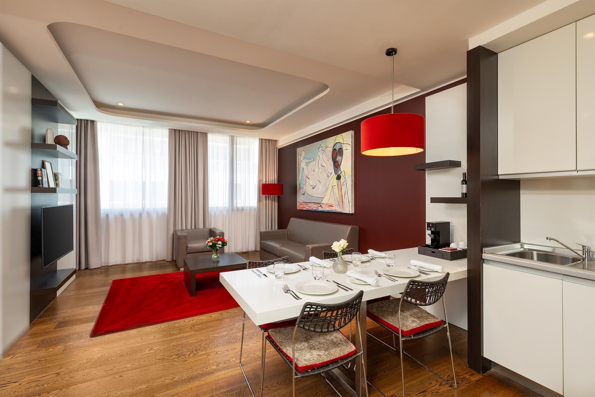 A modern hotel room with a dining area, a kitchen, and a living space.