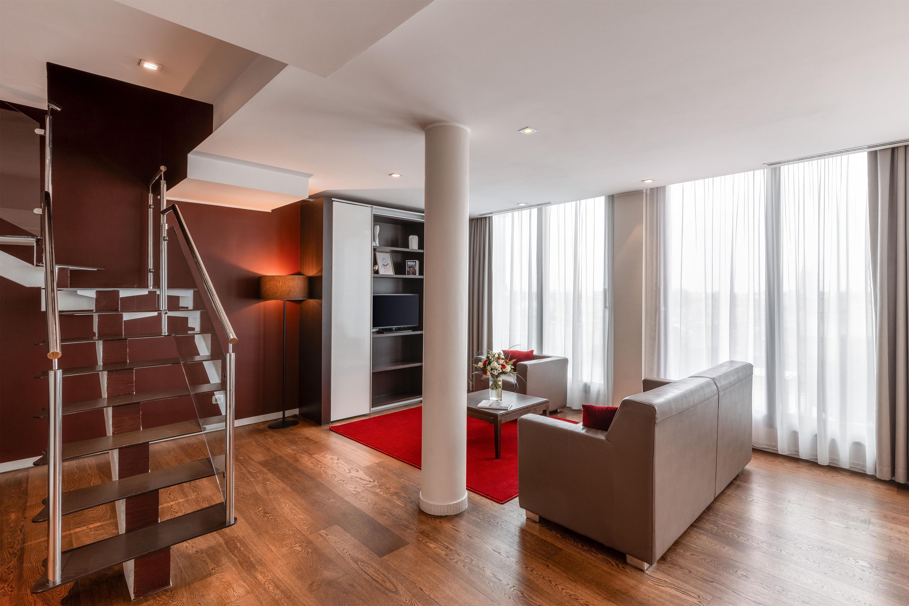 A modern living room with a staircase, a sofa, a coffee table, and a bookshelf.