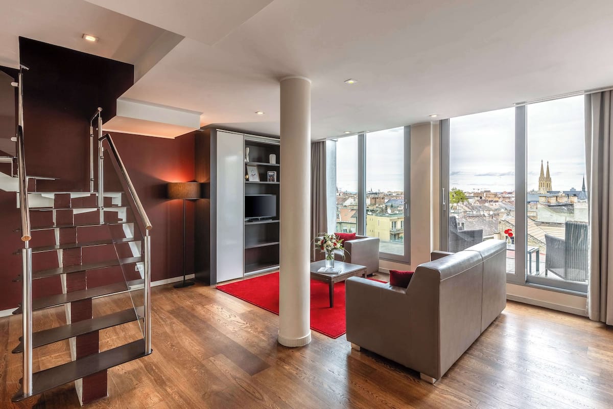 A modern living room with a staircase, a sofa, a coffee table, and a bookshelf.