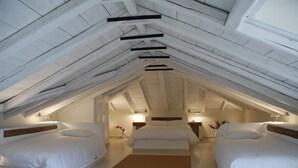 Ein Schlafzimmer mit zwei Betten, Holzbalken und einer schrägen Decke.