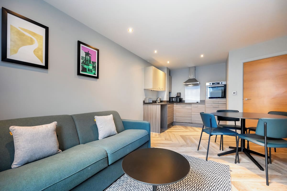 A modern living room with a sofa, a coffee table, and a dining area with chairs and a table.