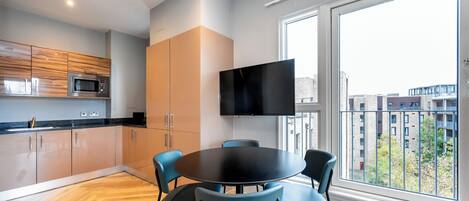 Eine moderne Küche mit Flachbildfernseher, Holzschränken und einem Essbereich mit Stühlen.