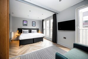 A modern bedroom with a large bed, a TV mounted on the wall, and a view of the city through the window. - Staycity Aparthotels, Edinburgh, West End (Edinburgh)