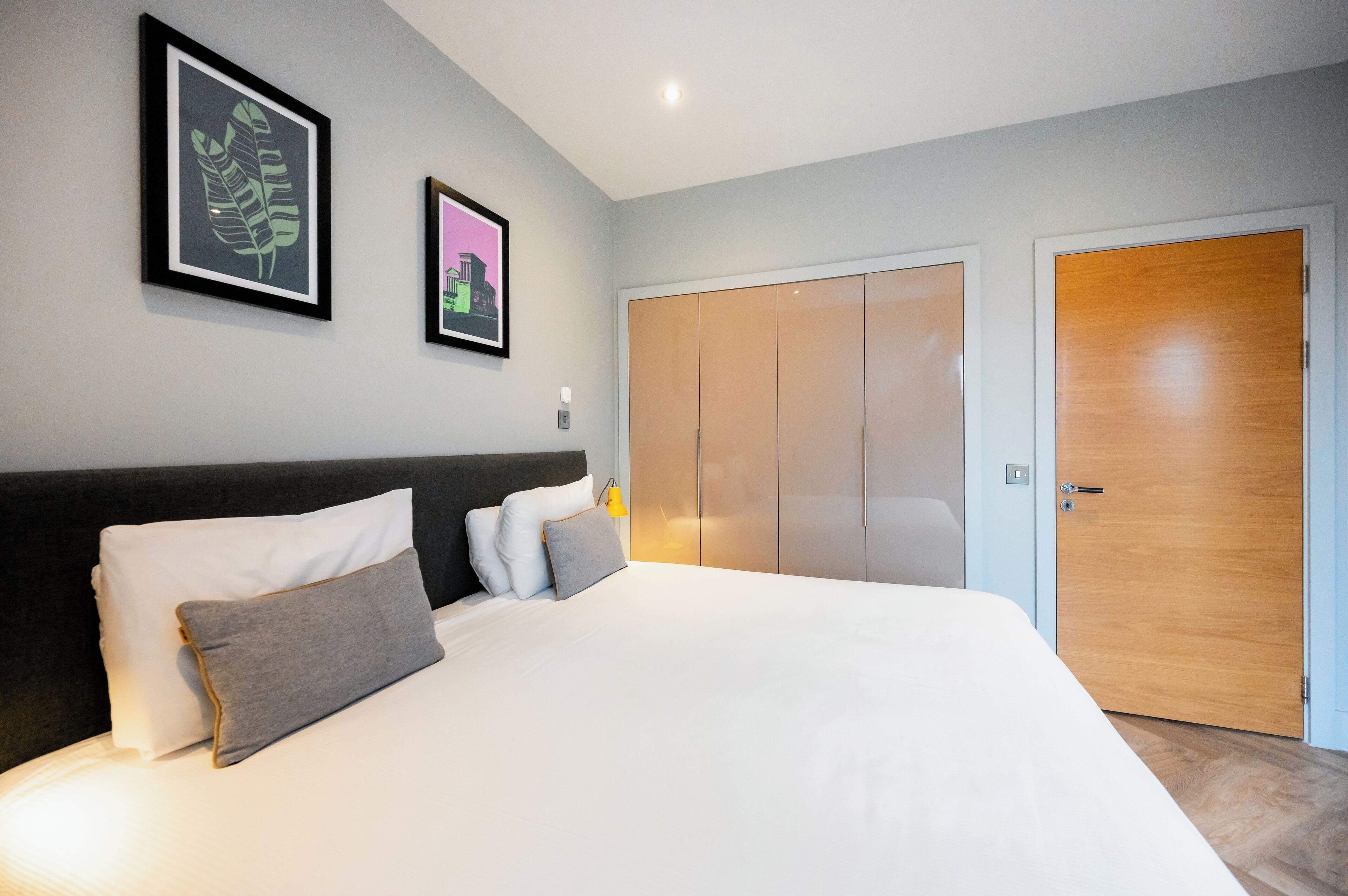 Une chambre à coucher moderne avec un grand lit, une armoire et deux tableaux encadrés accrochés au mur.