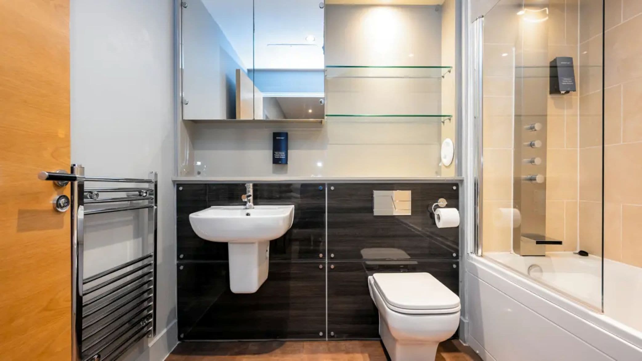 A modern bathroom with a white sink, toilet, and glass shower enclosure.