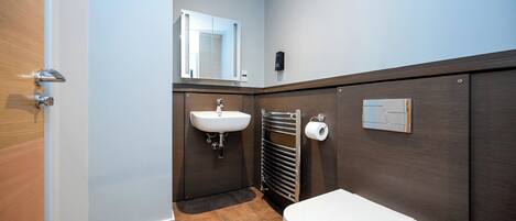 Une salle de bain avec un lavabo blanc, des toilettes et un porte-serviettes.