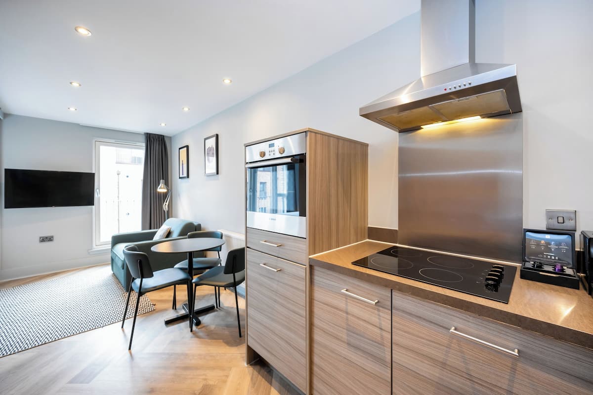 A modern kitchen with a built-in oven, a stove, and a microwave. There is a dining area with a table and chairs.