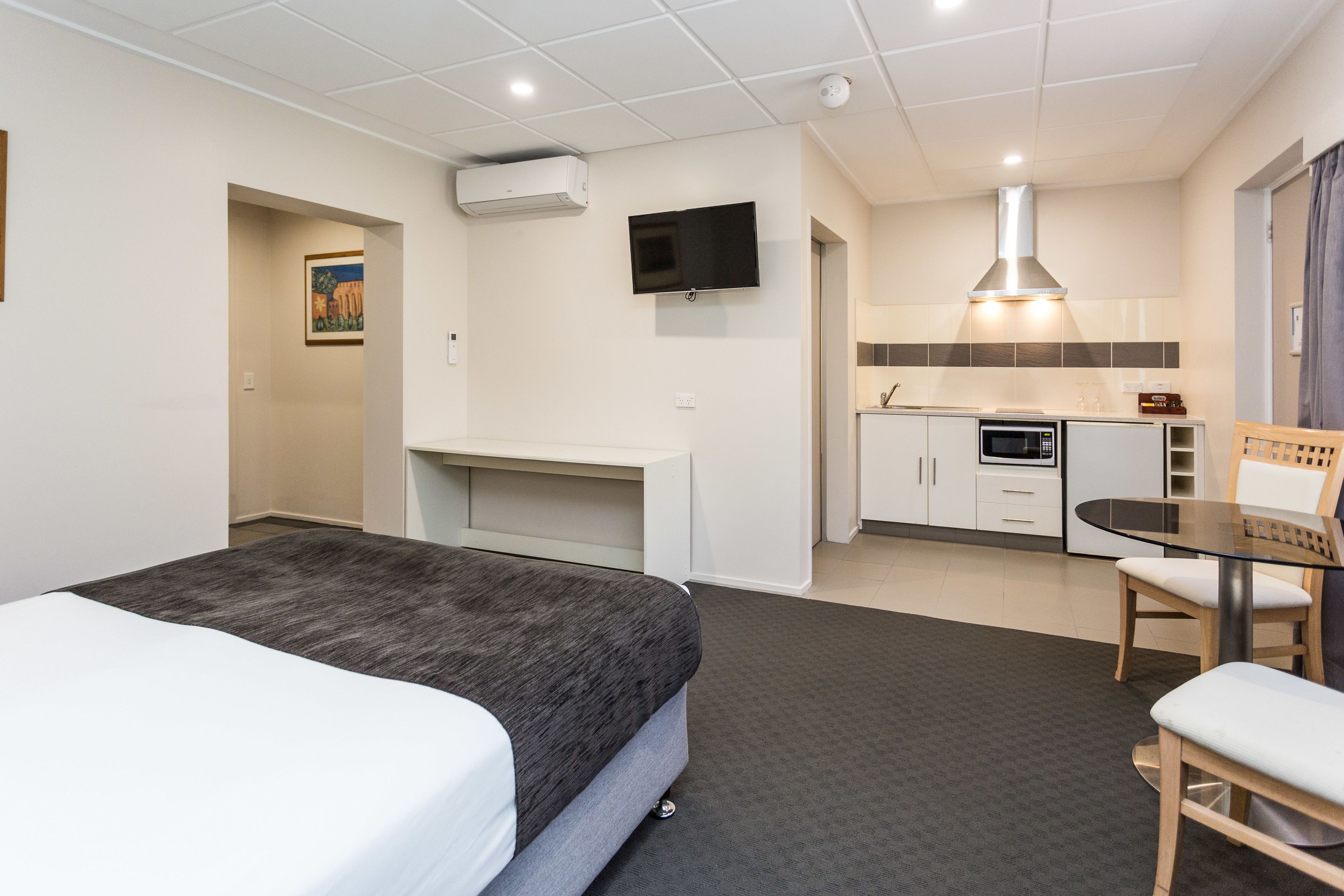 Une chambre d’hôtel équipée d’un lit, d’un bureau, d’une télévision, d’une kitchenette et d’un coin repas.