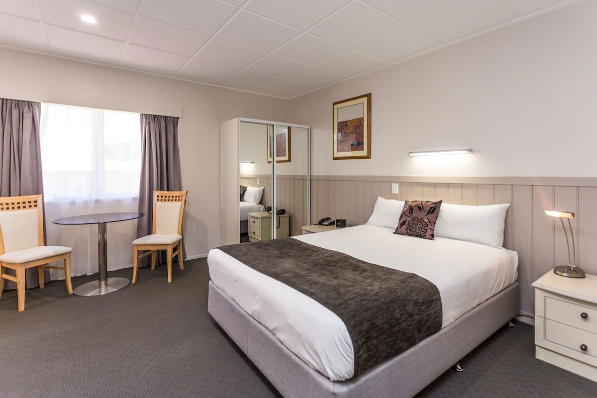 Escritorio, cortinas blackout y tabla de planchar con plancha