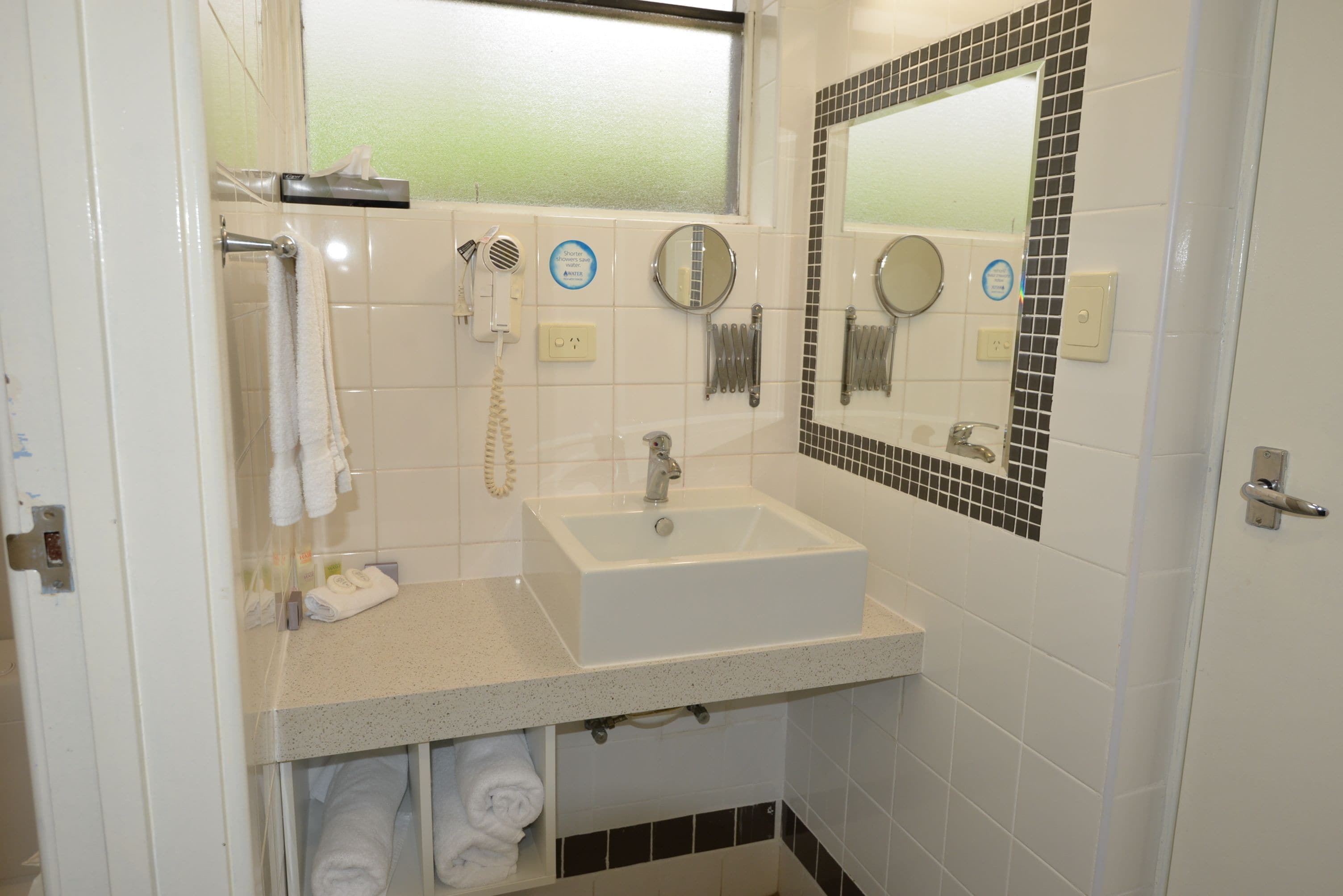 A bathroom with a sink, towel rack, and two mirrors.