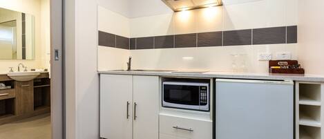 A modern kitchen with white cabinets, a built-in microwave, and a stainless steel range hood.