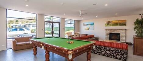 A pool table in a room with a sofa and a fireplace.