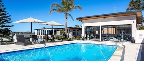 Una piscina al aire libre, sillones reclinables de piscina