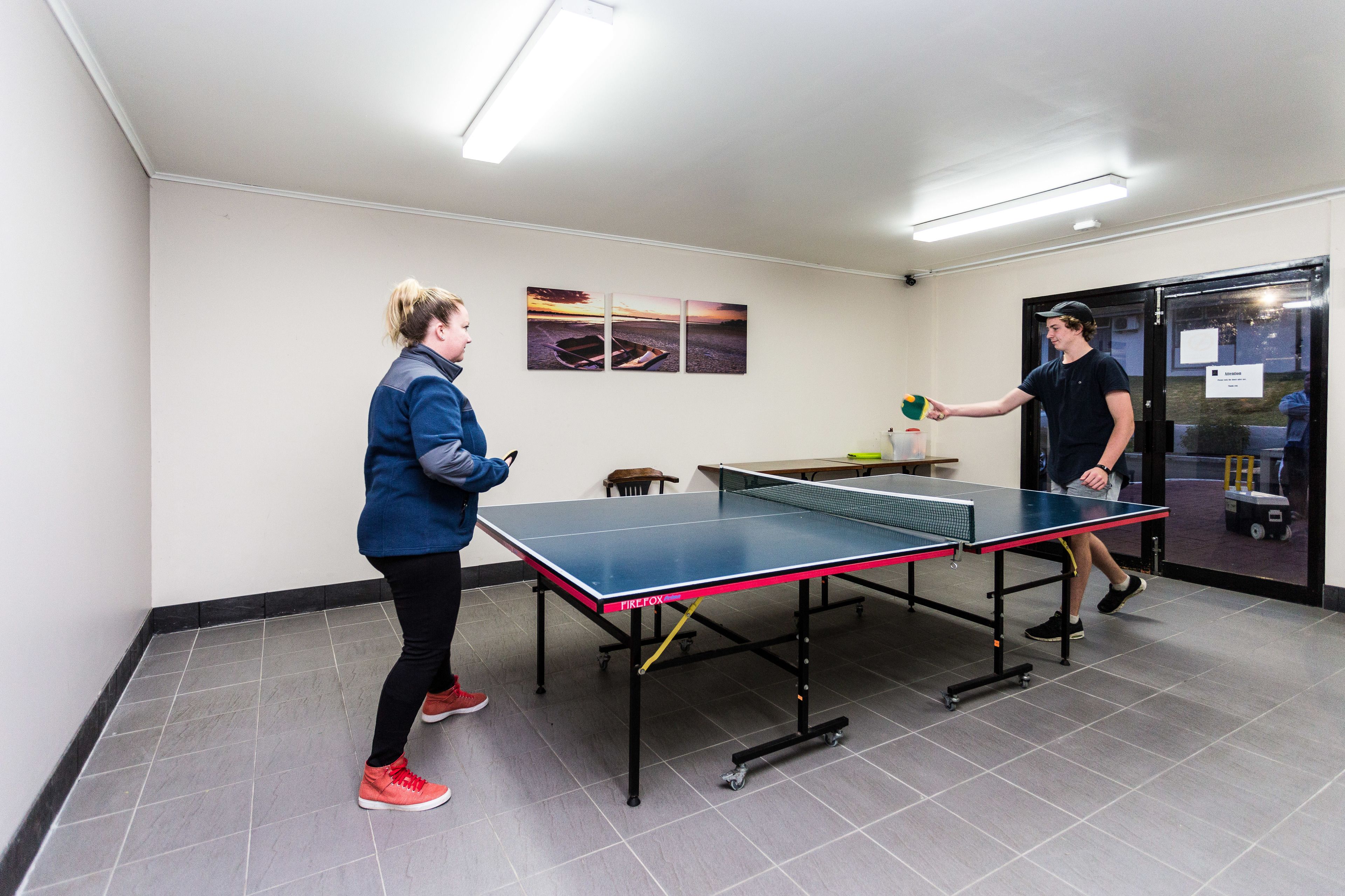 Taula de ping-pong en una habitació amb sòl de rajola i parets blanques.