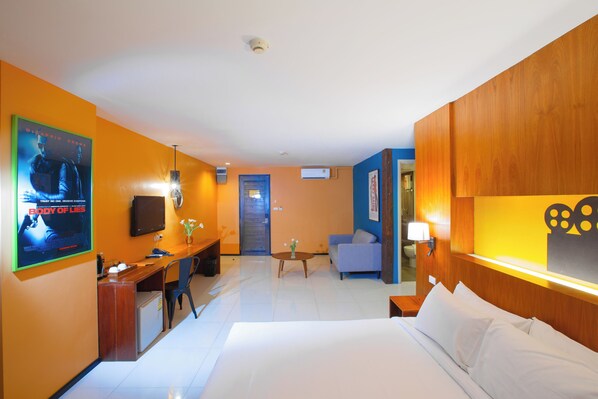 A hotel room with a bed, a desk, a chair, a sofa, a TV, and a poster on the wall. - MeStyle Place Hotel (Bangkok)