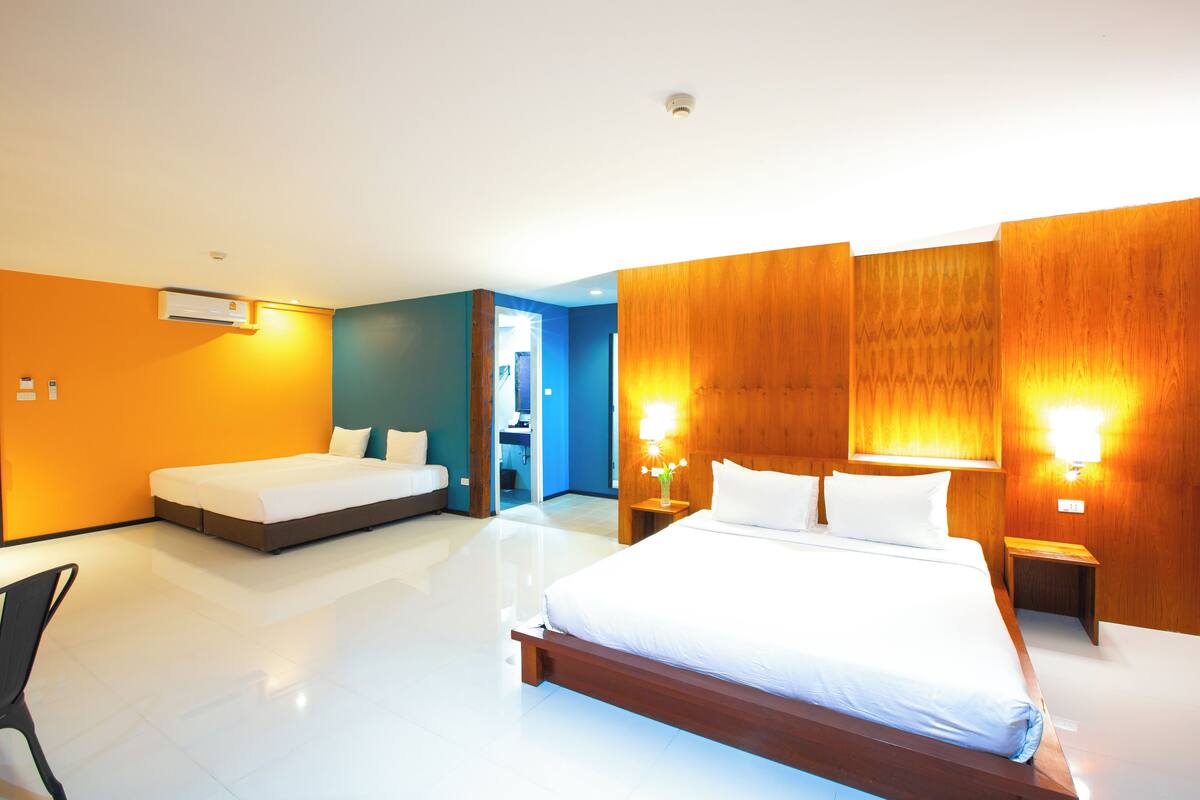 A modern hotel room with a large bed, a smaller bed, a desk, and a chair.