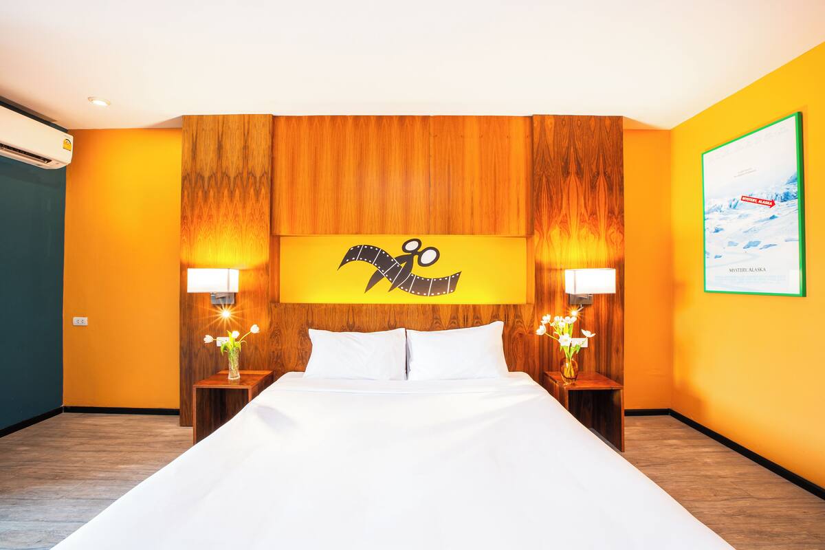 A hotel room with a large bed, two bedside tables with lamps, a wall-mounted TV, and a framed picture on the wall.