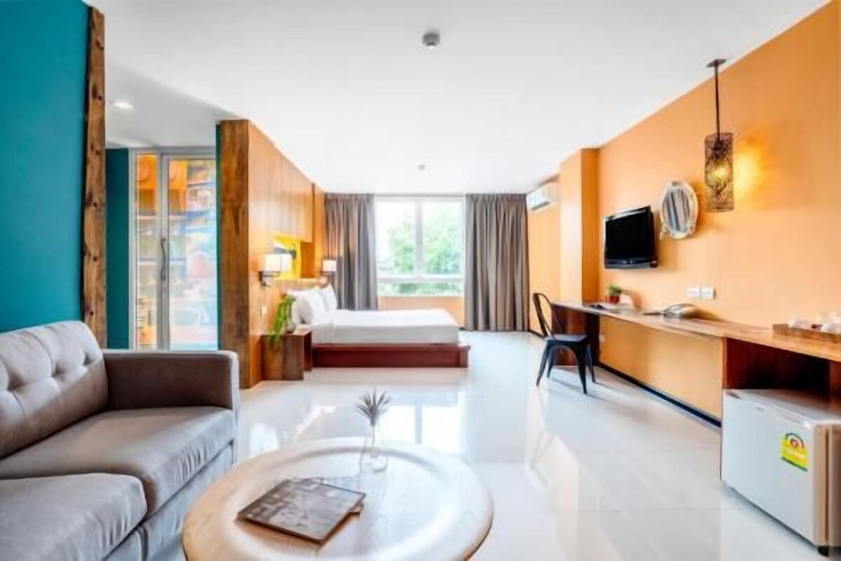 A modern hotel room with a sofa, a bed, a desk, and a TV.