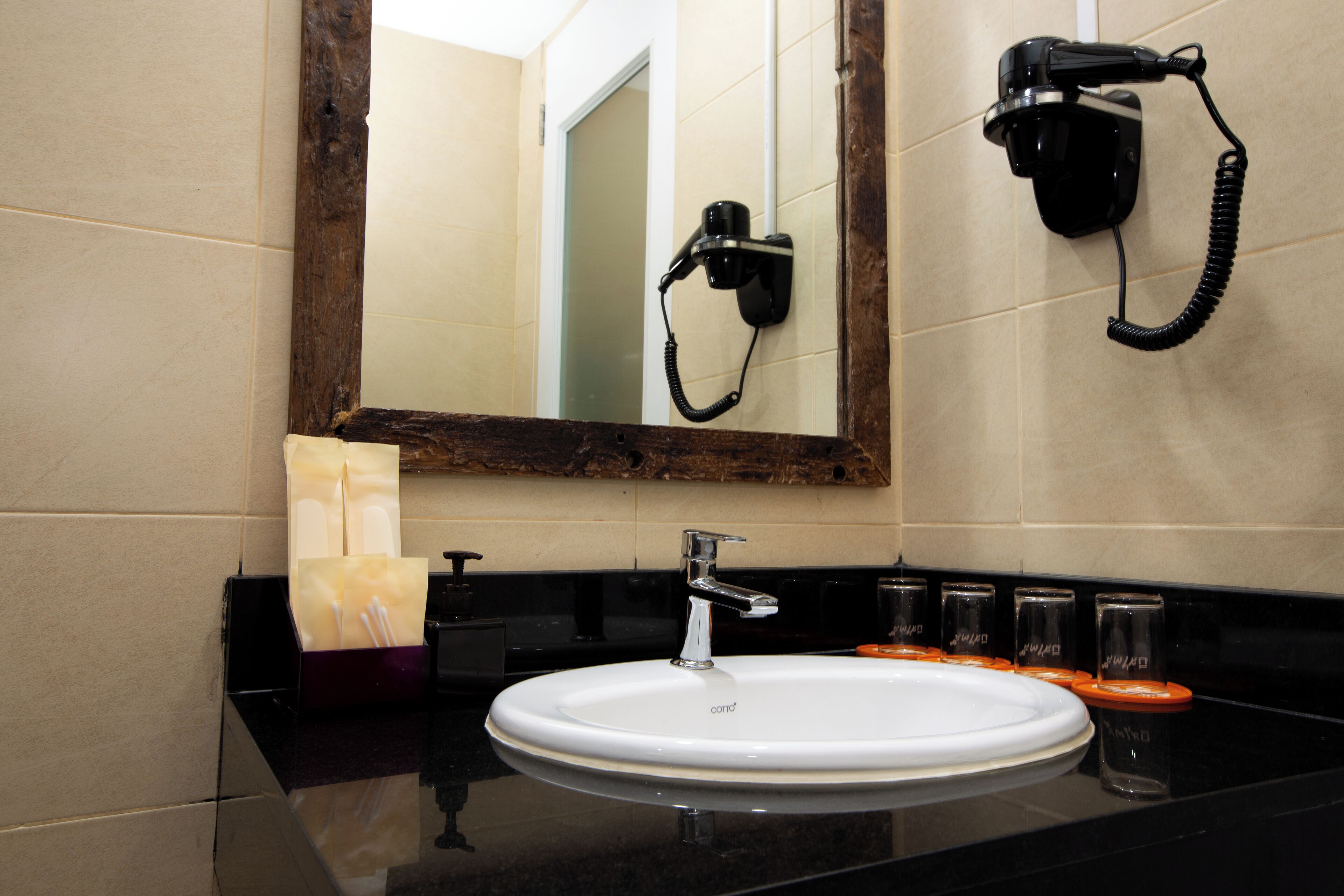 A bathroom with a white sink, a mirror, and a hairdryer mounted on the wall.