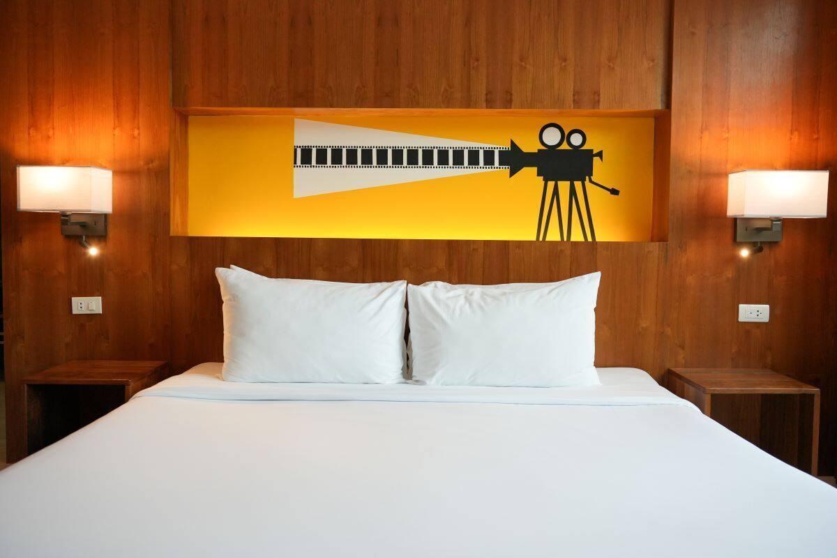 A hotel room with a wooden headboard, two bedside lamps, and a large bed with white bedding.