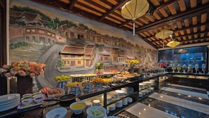 Un bufé con diferentes opciones de comida y un mural que representa una escena de un pueblo tradicional.