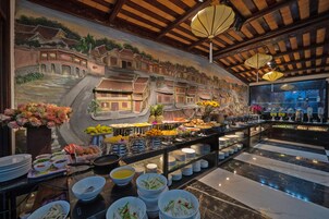 Un bufé con diferentes opciones de comida y un mural que representa una escena de un pueblo tradicional.
