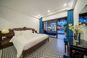 Habitación de hotel con una cama grande, un escritorio con un florero y vistas al exterior a través de un ventanal.