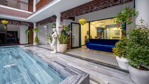 Amplio espacio interior con piscina, sofá azul y plantas en macetas.