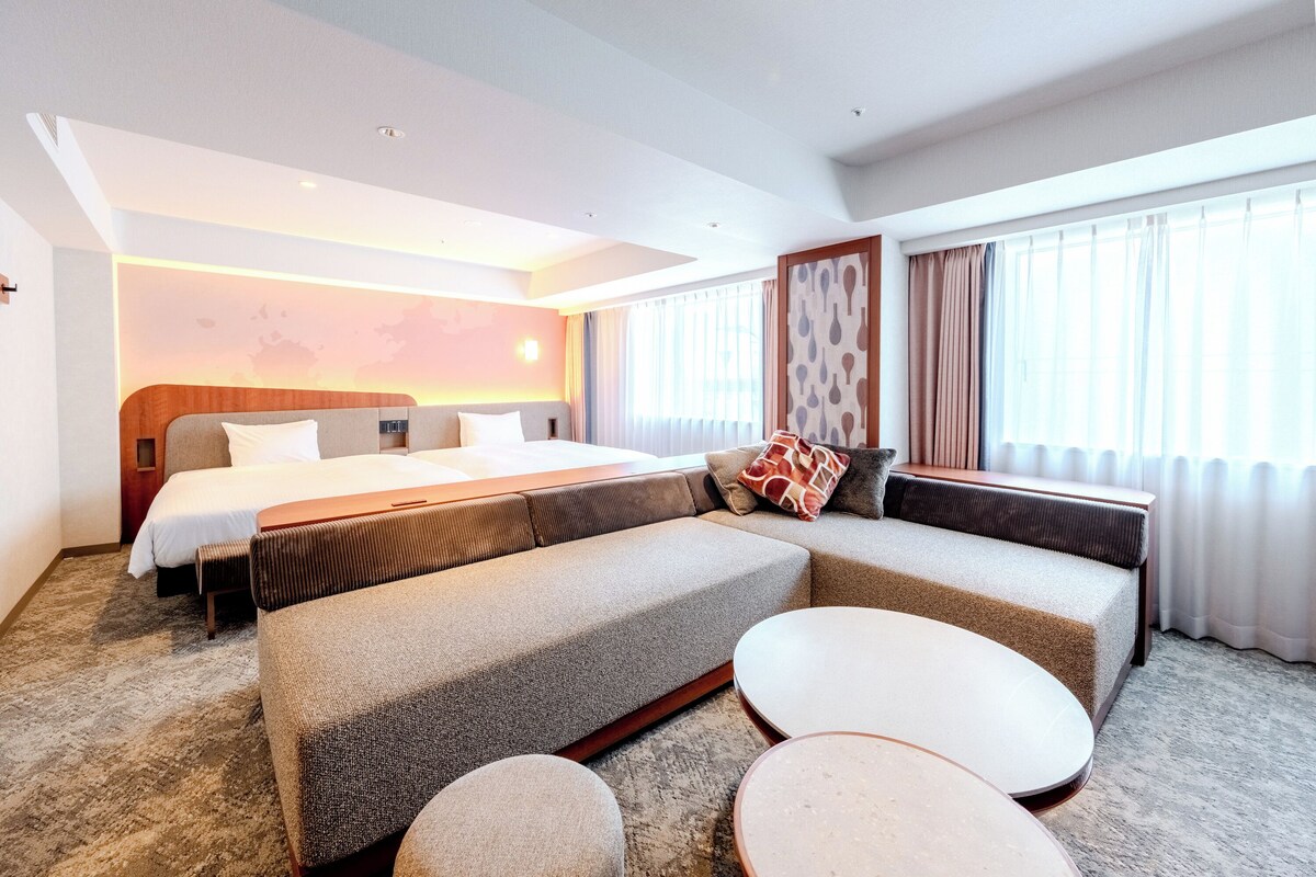 Una habitación de hotel moderna con una cama grande, un sofá y una mesita.