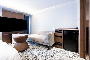 A hotel room with a bed, a flat-screen TV, a sofa, a desk, and a refrigerator. - Richmond Hotel Fukuoka Tenjin (Fukuoka)