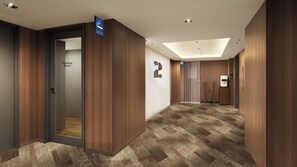 A hotel corridor with a smoking room sign, a wall-mounted hand sanitizer dispenser, and a patterned floor. - Richmond Hotel Fukuoka Tenjin (Fukuoka)