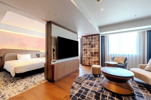 A modern hotel room with a bed, a flat-screen TV, a seating area with a sofa and armchair, and a patterned rug. - Richmond Hotel Fukuoka Tenjin (Fukuoka)