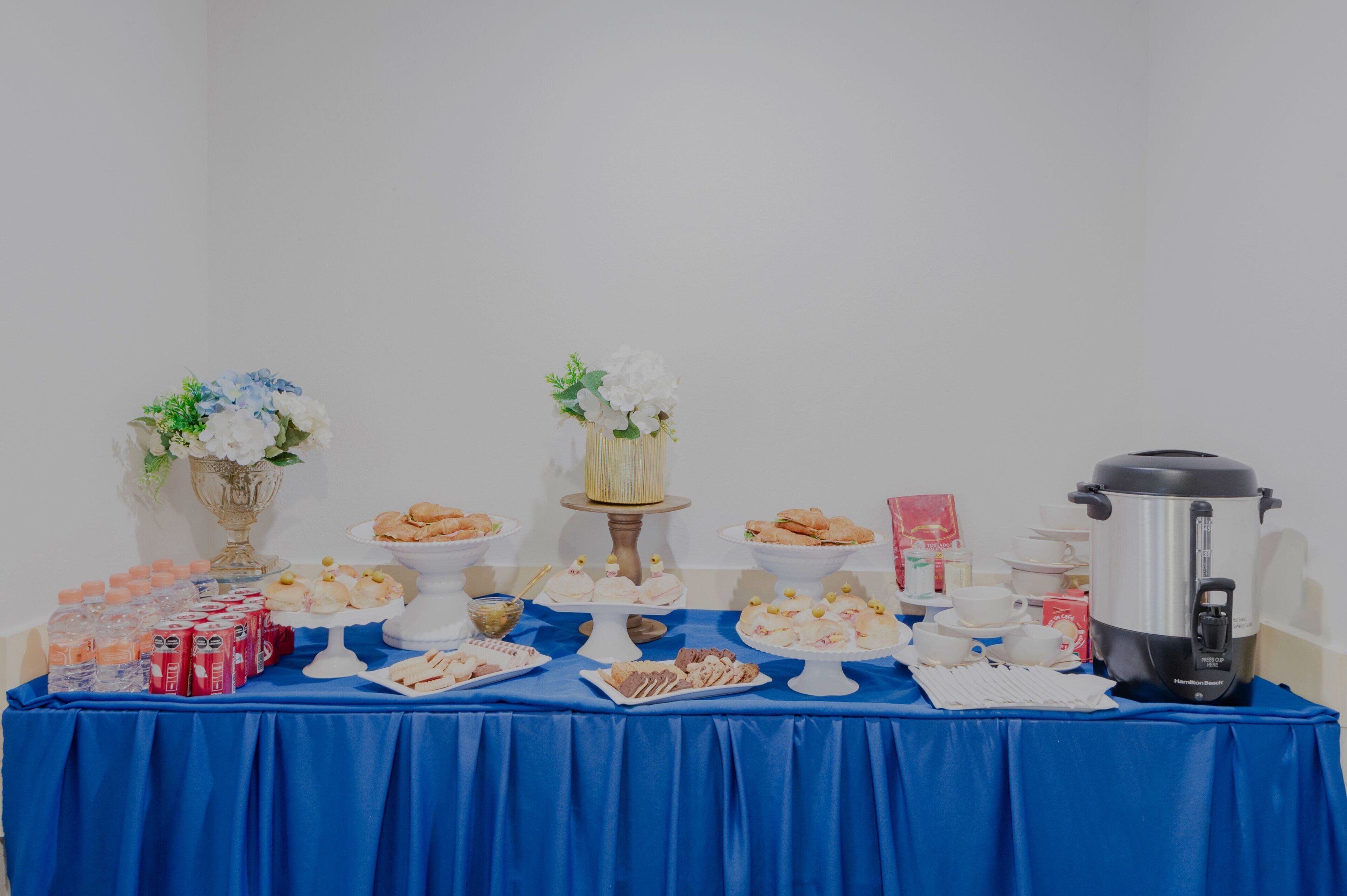 A buffet table with various food items, a coffee pot, and decorative flowers.