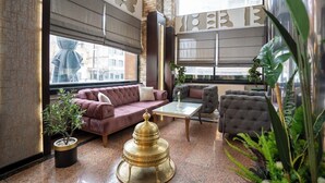A modern lounge with a sofa, armchair, and a decorative table. - Buyuk Velic Hotel (Gaziantep)