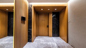 Un intérieur moderne avec une porte en bois portant l’inscription « SALLE DE RÉUNION », un sol en marbre et des panneaux de bois verticaux.