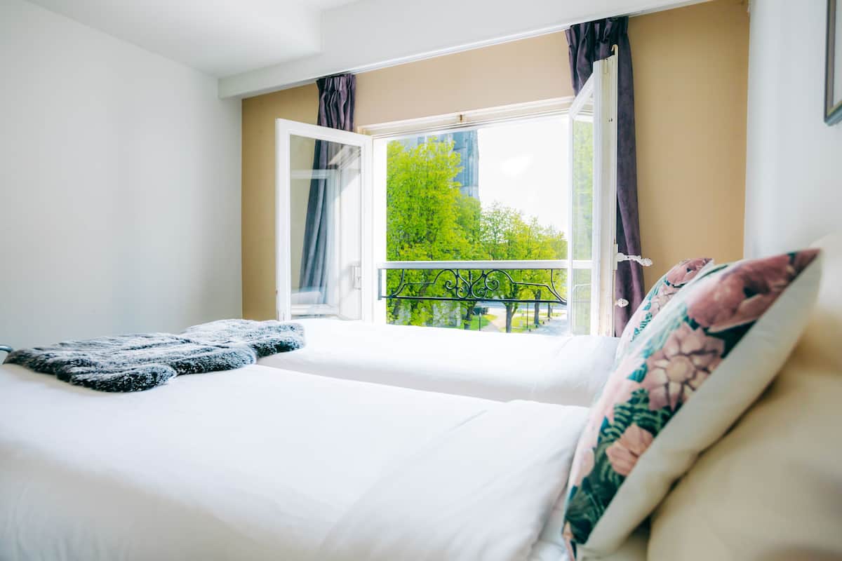 A bedroom with a bed, a window with curtains, and a view of trees outside.