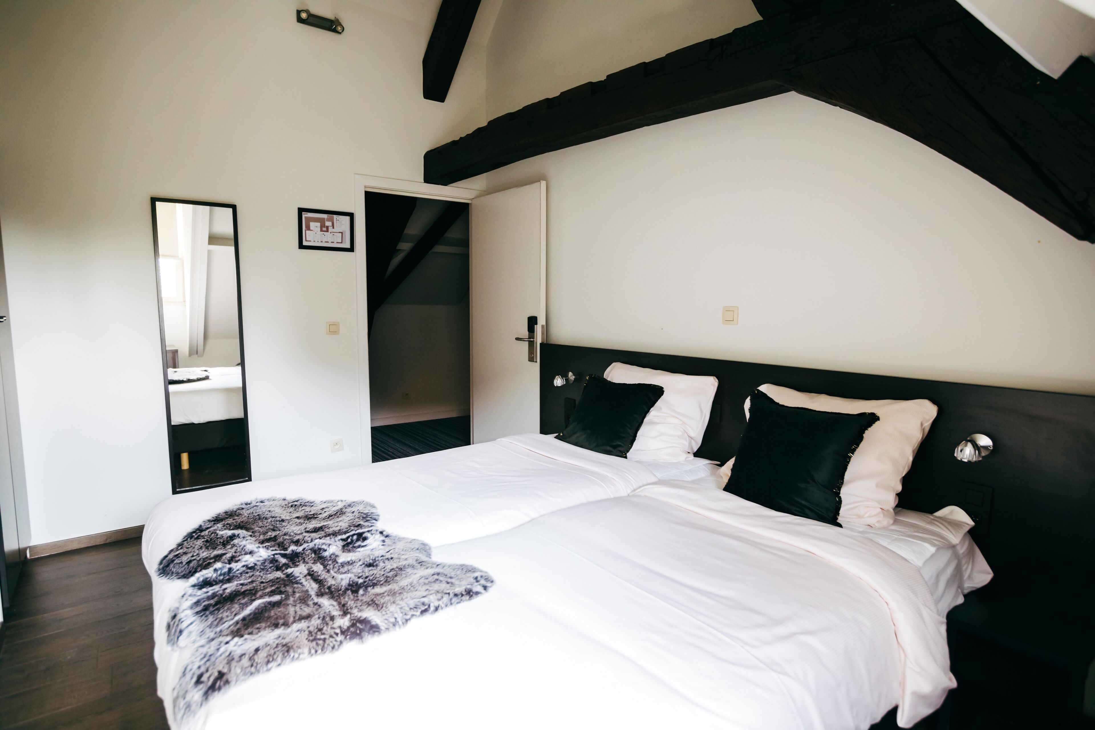 Een slaapkamer met een groot bed, een spiegel en een kledingkast.