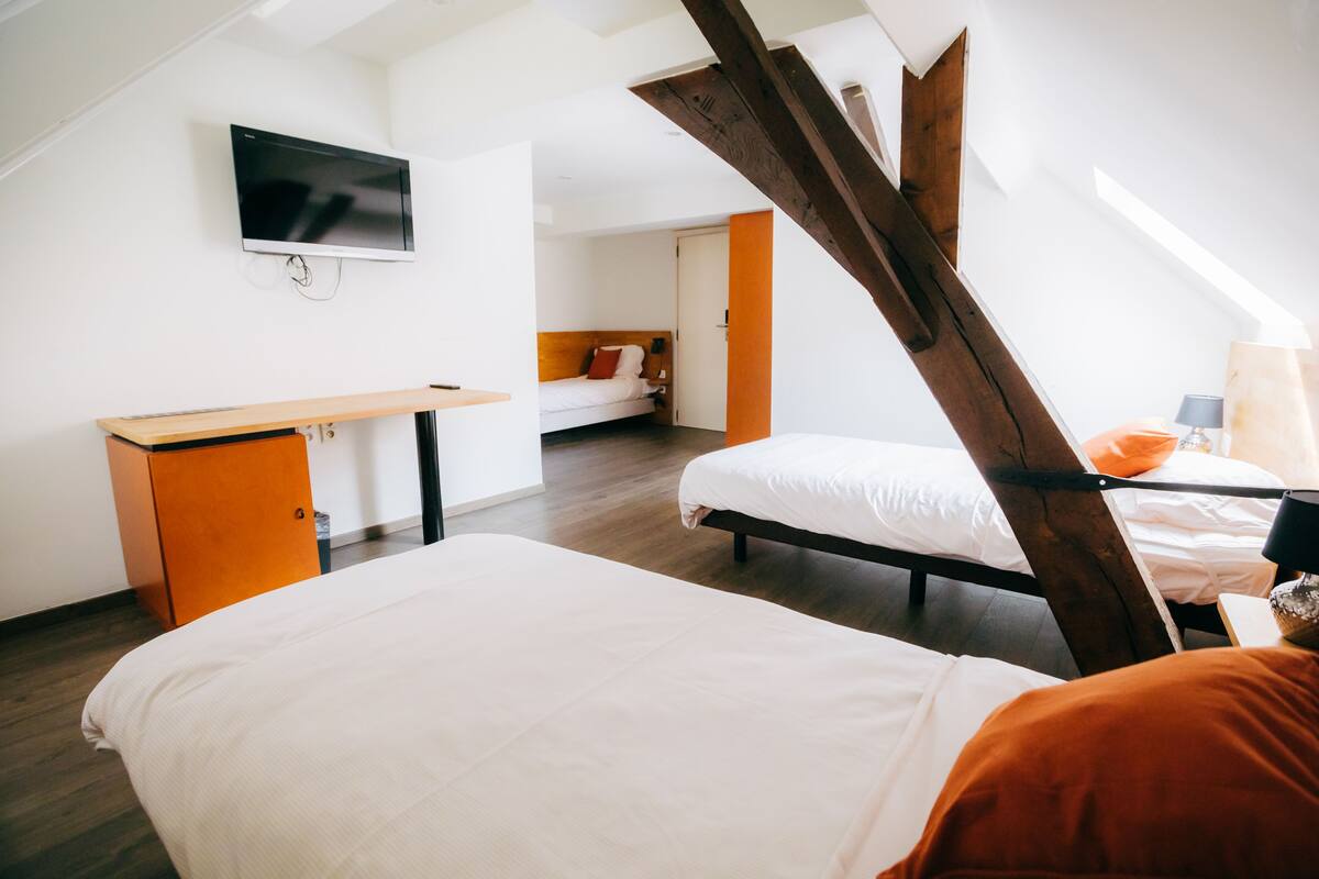A modern bedroom with a loft-style bed, a desk, and a television mounted on the wall.