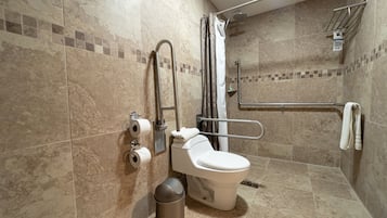 A bathroom with a toilet, grab bars, a shower, and a trash can.