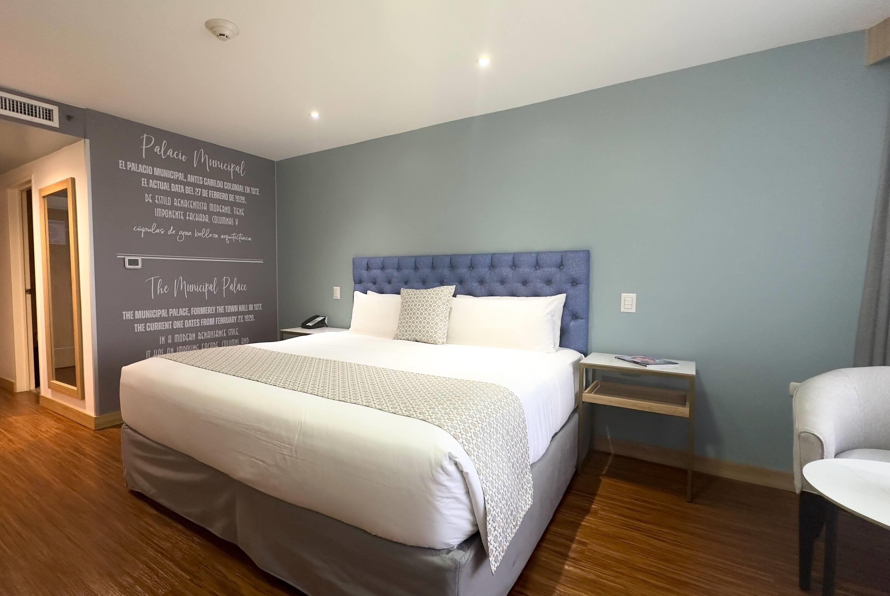 Una habitación de hotel moderna con una cama grande, una mesita de noche y una silla.