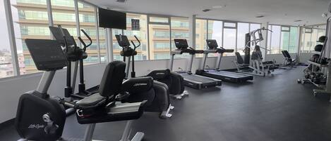Un gimnasio con cintas de correr, máquinas de pesas y mancuernas.