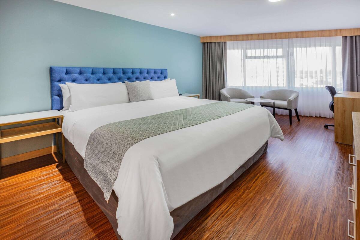 Ein modernes Hotelzimmer mit einem großen Bett, einem Schreibtisch und einem Sessel.
