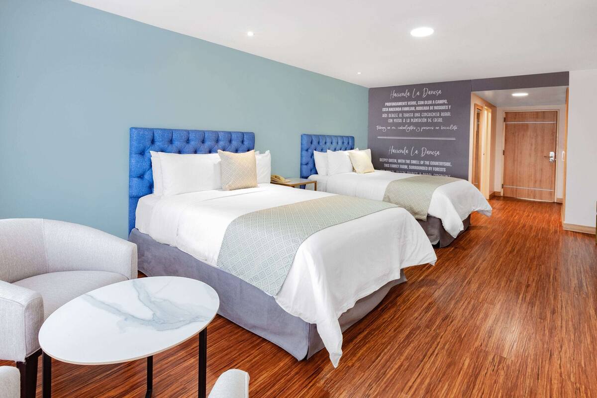 Ein Hotelzimmer mit zwei Betten, einem kleinen runden Tisch und einem Stuhl.