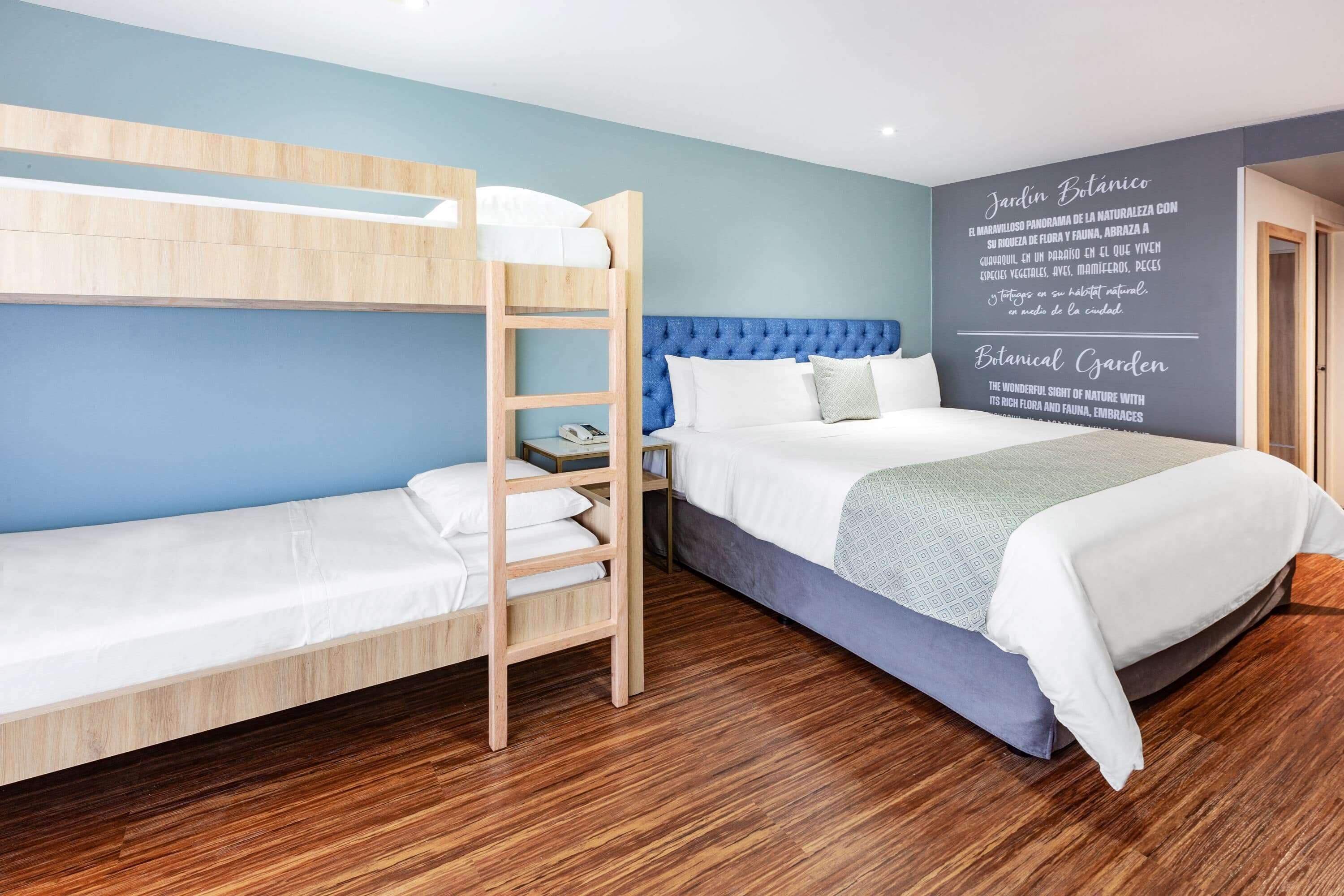 A room with a bunk bed, a single bed, and a wall with text about a botanical garden.