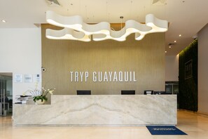 Un comptoir d’accueil avec un plateau en marbre et un luminaire moderne placé au-dessus.